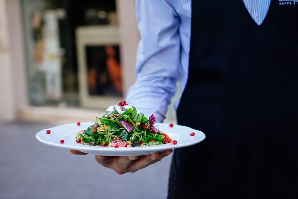 A waiter serves a plate of salad